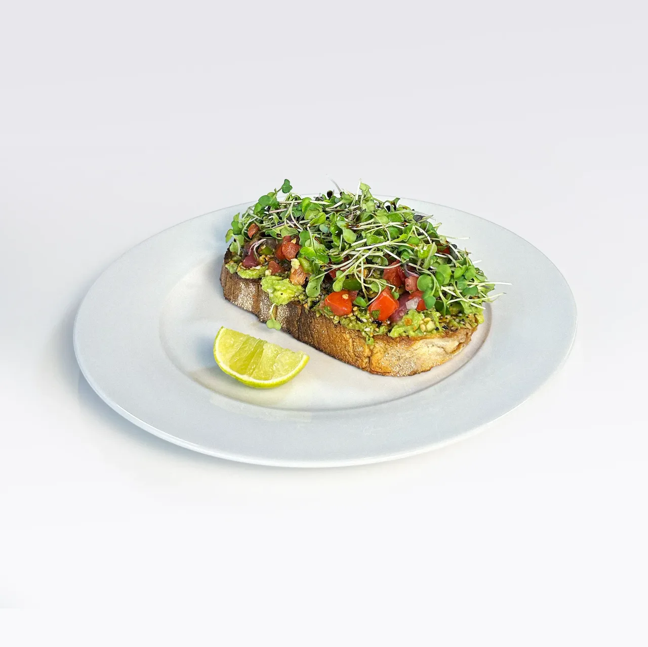 EVO Toast topped with pico de gallo and microgreens, with a lime wedge