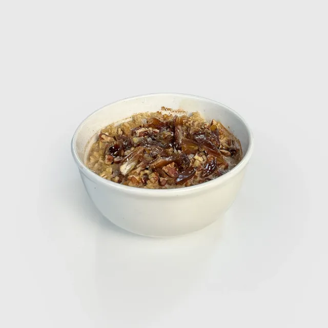 A bowl of oats topped with medjool dates, toasted pecans and dark maple